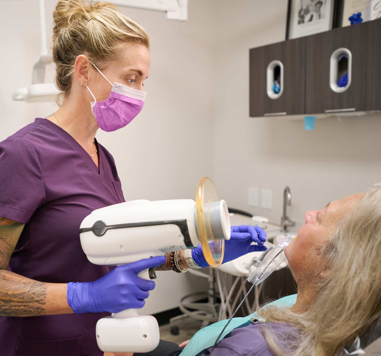Harrison Family Dental team member positioning a handheld digital X-ray unit for a patient in the dental chair