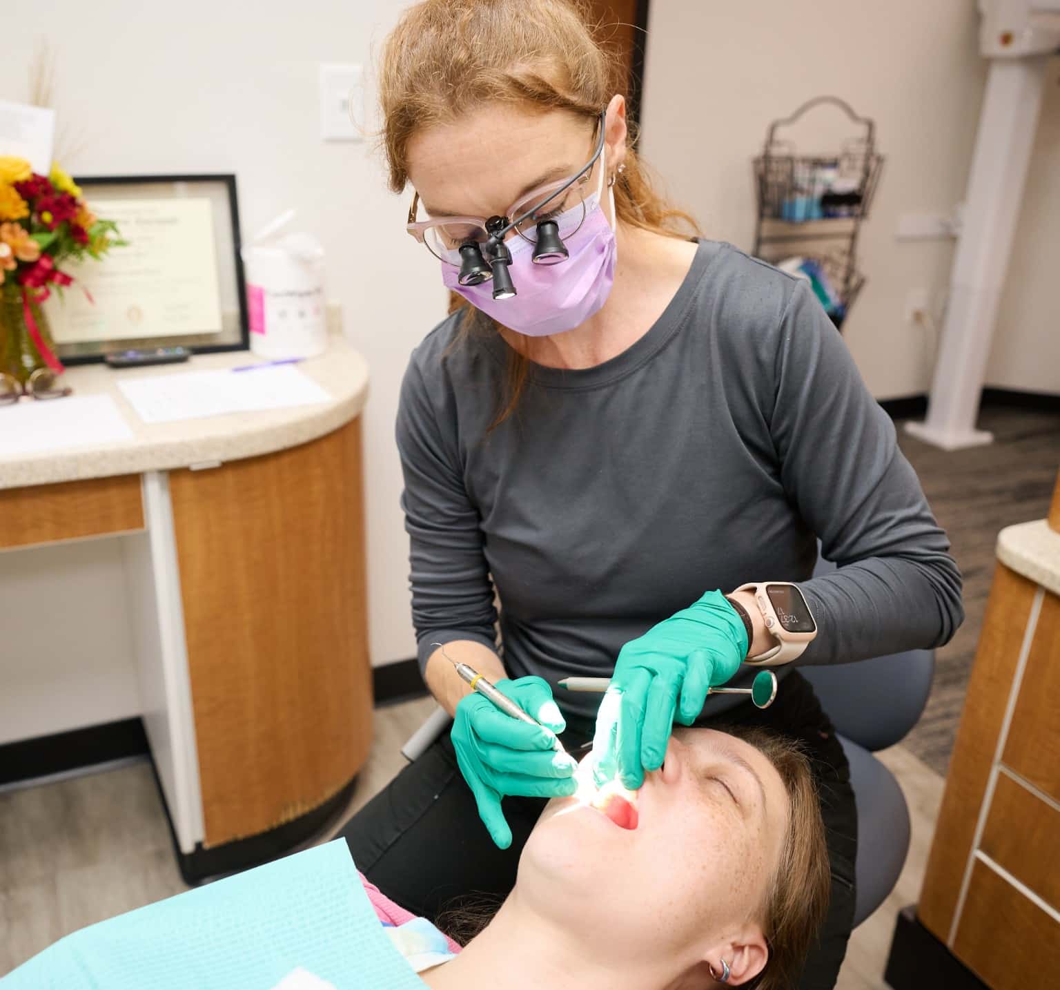 Harrison Family Dental team member wearing magnifying loupes treating a patient reclined in the dental chair